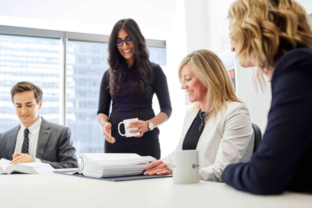 Office employees (3 women and 1 man) in a boardroom having a meeting. 