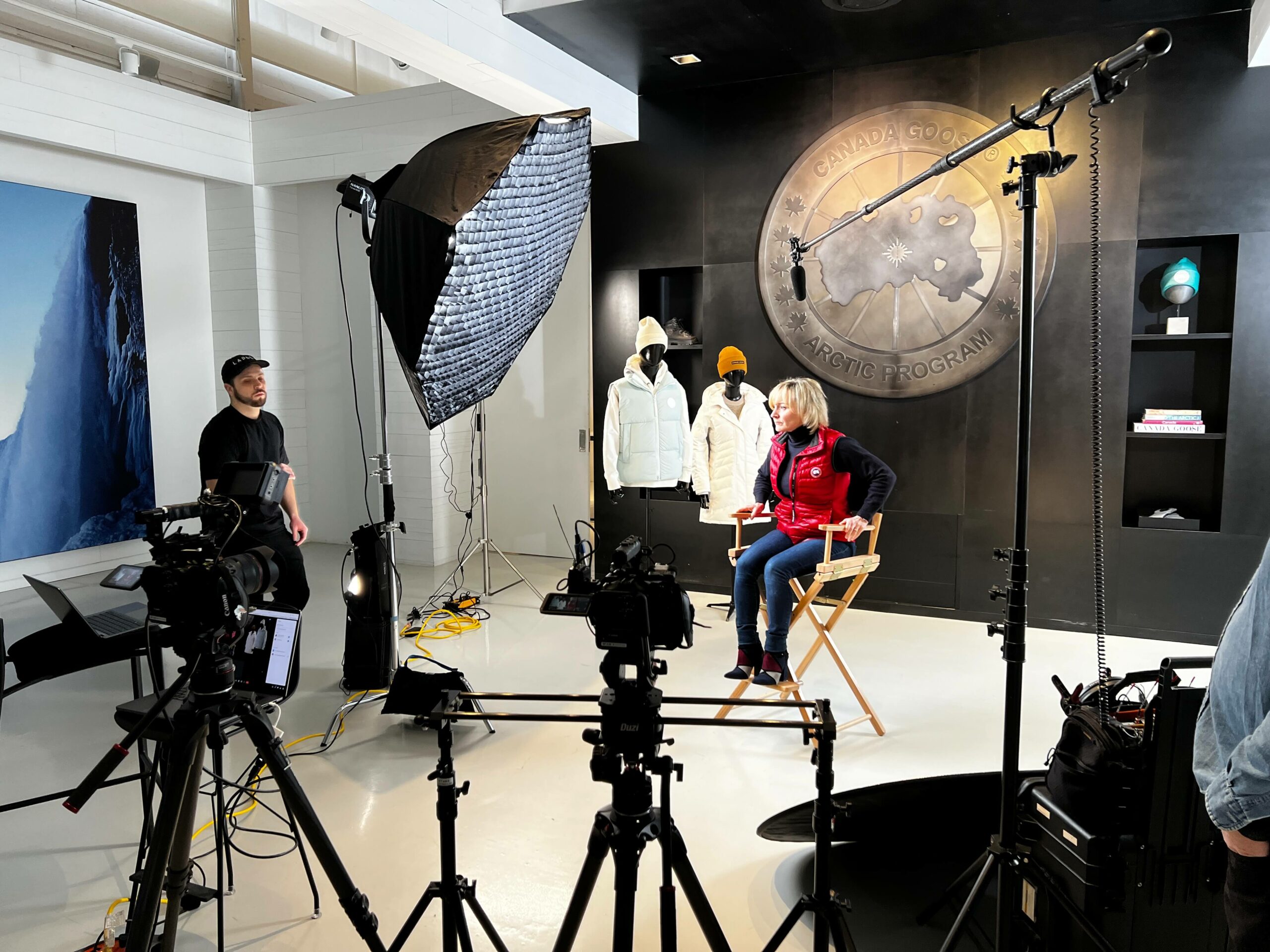 Behind-the-scenes image of a Canada Goose executive being interviewed at the Canada Goose headquarters in Toronto, with cameras visible in the shot.