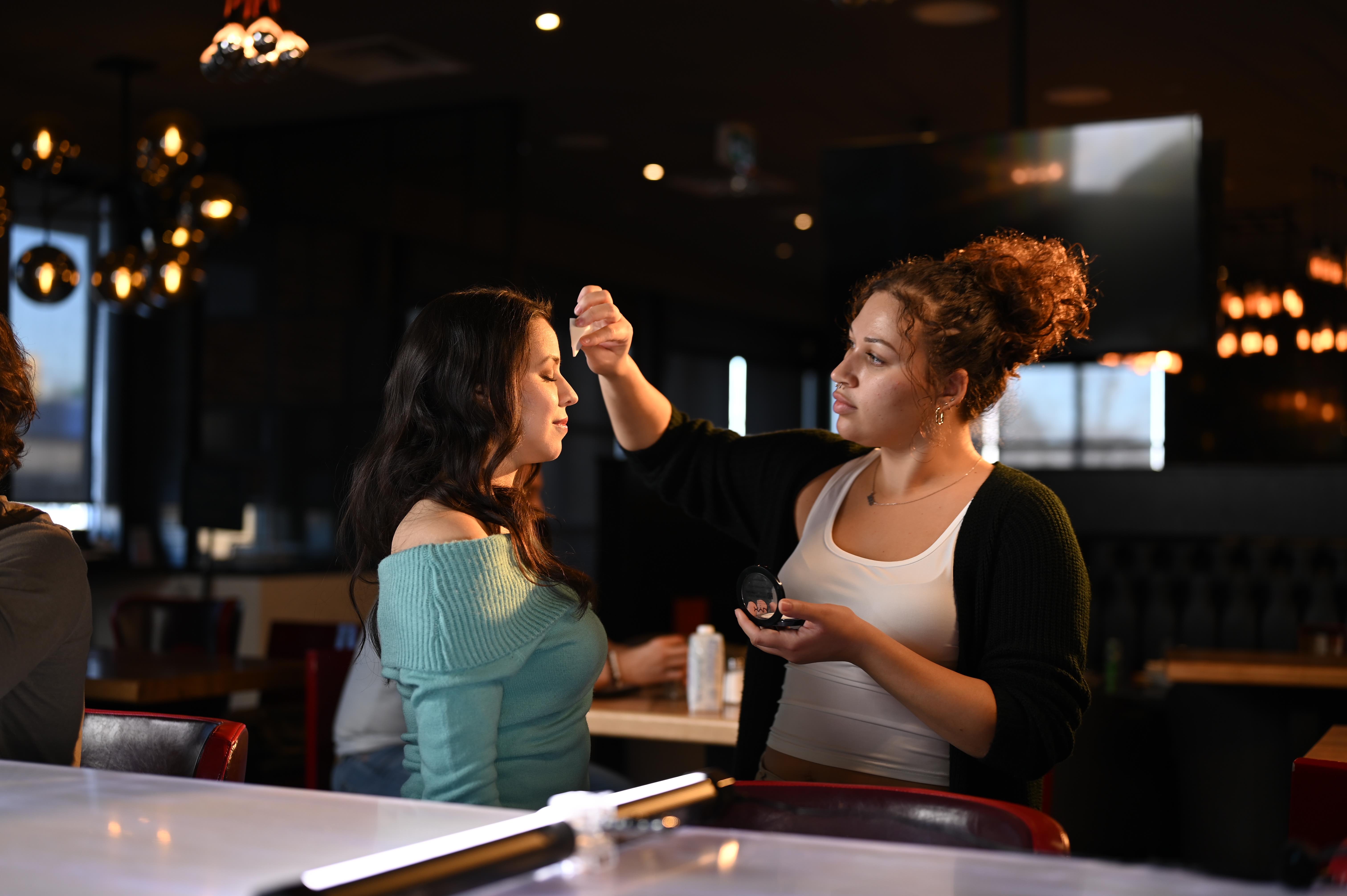 Makeup Artist from Lapse Productions Applying Makeup to an Actress On-Set in a Restaurant