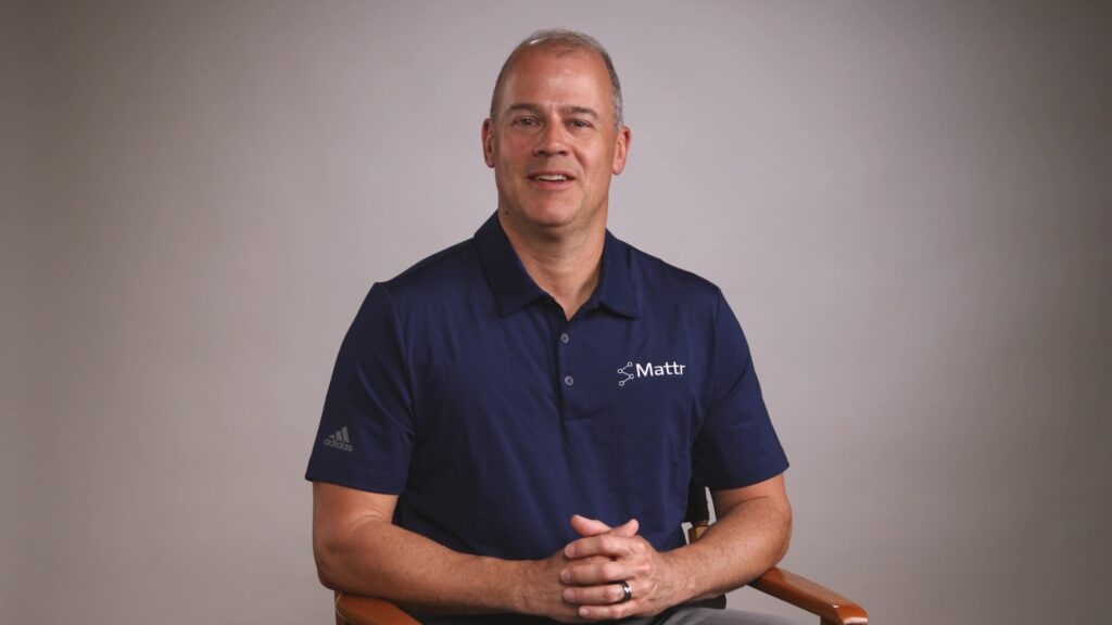 A confident CEO demonstrating the power pose with hands touching against a backdrop.