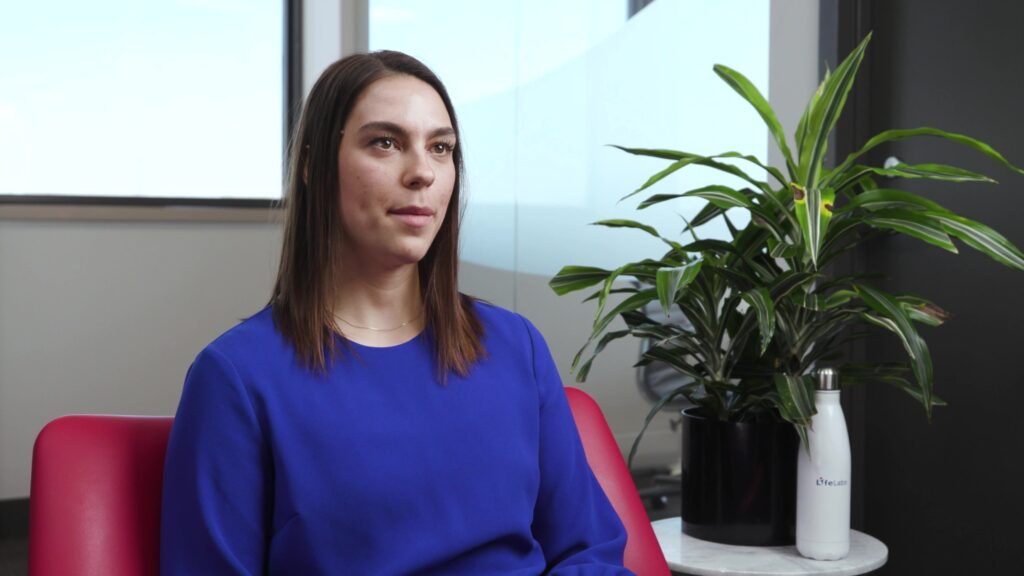 Corporate interviewee in a relaxed pose, seated on a red chair, facilitating an informal discussion.