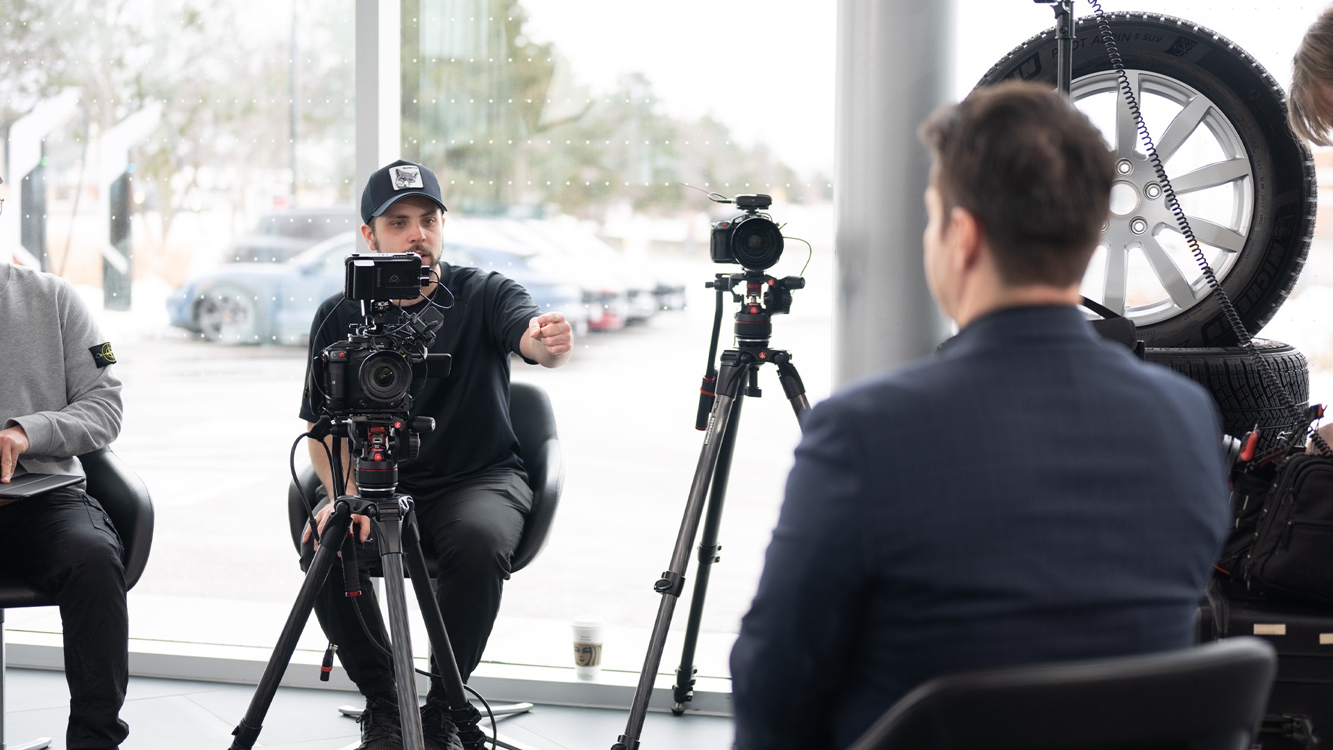 Cinematographer from Lapse Productions directing the corporate interviewee on his positioning. Two canon camera's are on tripods. The location is at a car dealership.